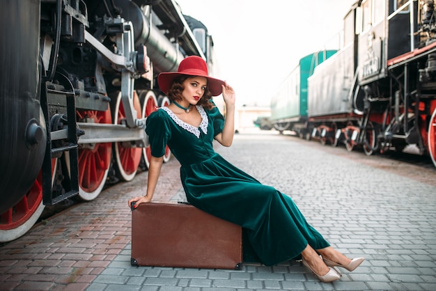 Mulher sentada na mala contra o trem a vapor