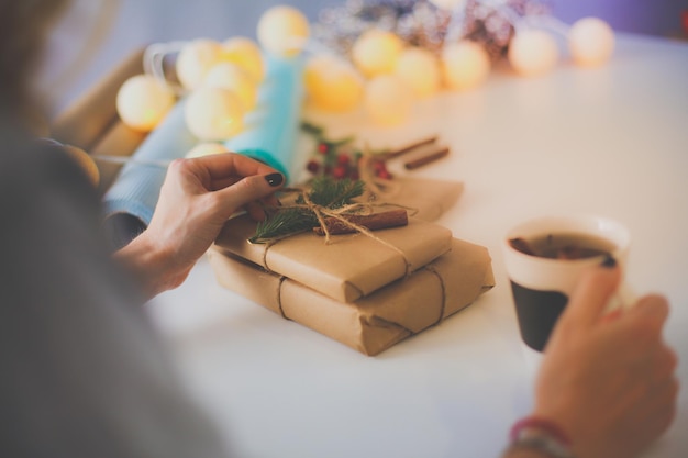 Mulher sentada na mesa com caixa de presente de natal Mãos de mulher