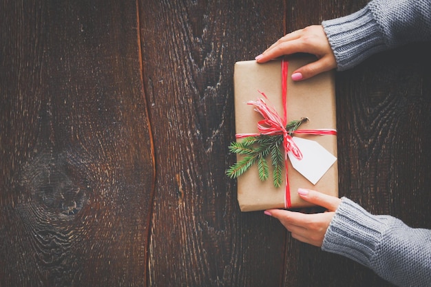 Mulher sentada na mesa com caixa de presente de natal Mãos de mulher