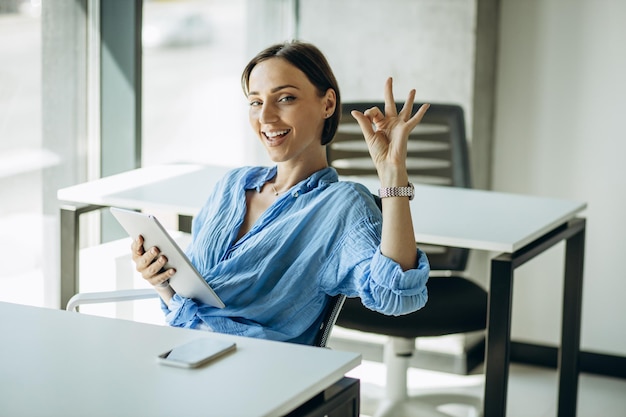 Mulher sentada na mesa do escritório e usando tablet