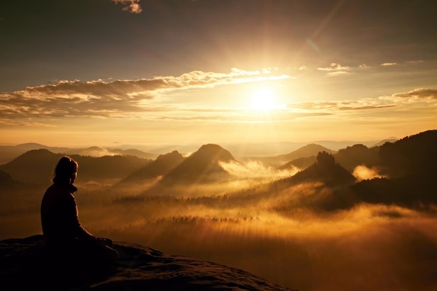 Foto mulher sentada na montanha contra o céu durante o pôr do sol