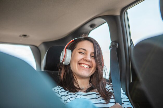 Foto mulher sentada na parte traseira do carro senta-se ouvindo música com fone de ouvido cópia espaço dia ensolarado