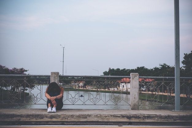 Foto mulher sentada na ponte com sentimento triste