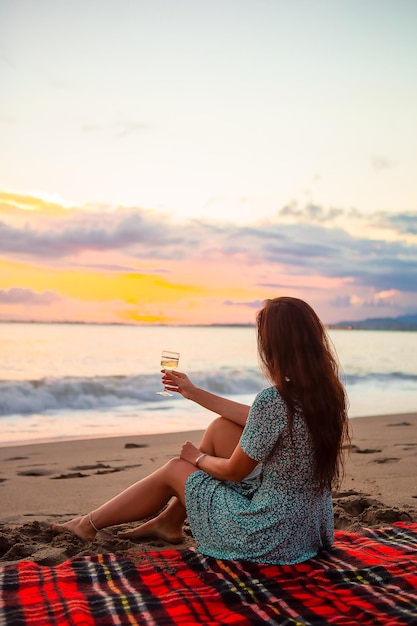 Foto mulher sentada na praia contra o céu durante o pôr-do-sol