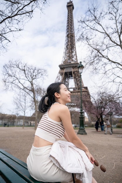 Mulher sentada no banco perto da Torre Eiffel Paris França