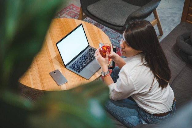 Mulher sentada no café usando laptop bebendo chá. Tela branca. copie o espaço. estilo de vida