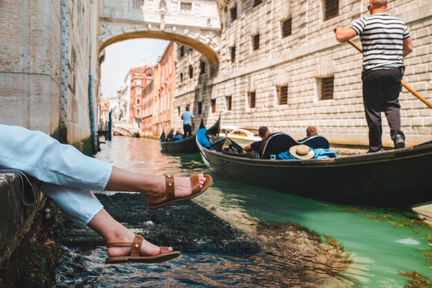 Mulher sentada no cais da cidade em veneza itália apreciando a vista dos canais com espaço de cópia de gôndolas