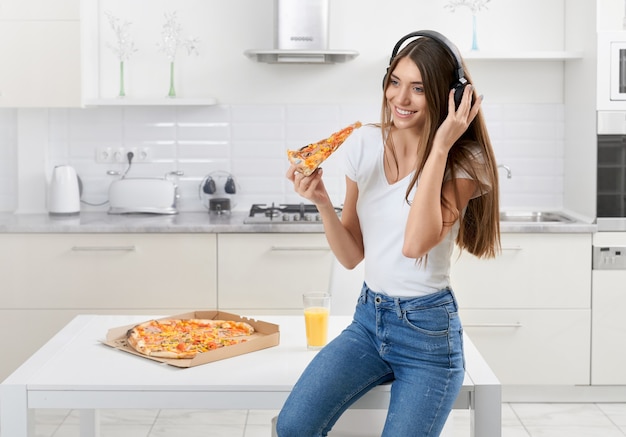 Mulher sentada no fone de ouvido comendo uma pizza saborosa