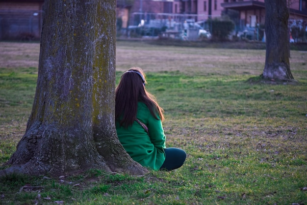 Mulher sentada no parque meditando pensativo e ouvindo música em fones de ouvido