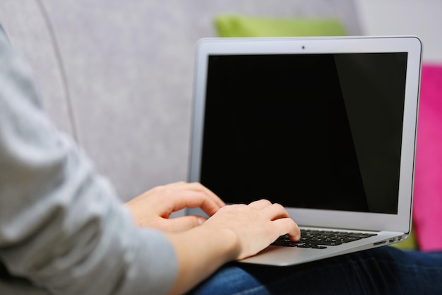 Mulher sentada no sofá com um laptop em uma sala