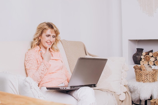 Mulher sentada no sofá e trabalhando no laptop