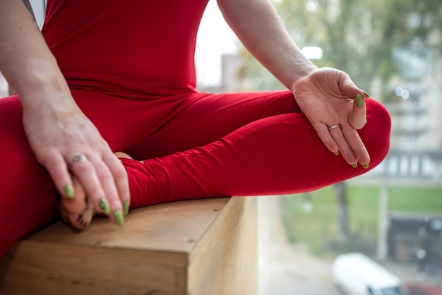 Mulher sentada no tapete na posição padmasana e fazendo ioga relaxa meditação em roupas esportivas vermelhas