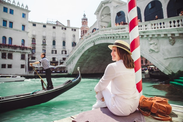 Mulher sentada perto da ponte rialto em veneza itália olhando para o grande canal com gôndolas