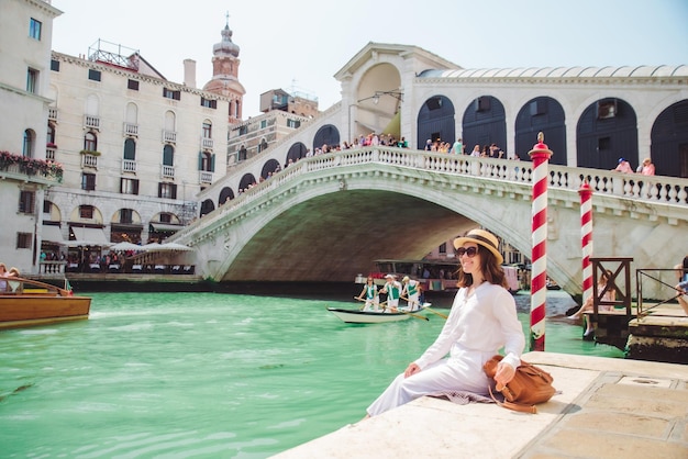 Mulher sentada perto da ponte rialto em veneza itália olhando para o grande canal com gôndolas