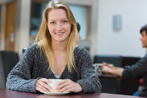 Mulher sentada tomando uma xícara de café