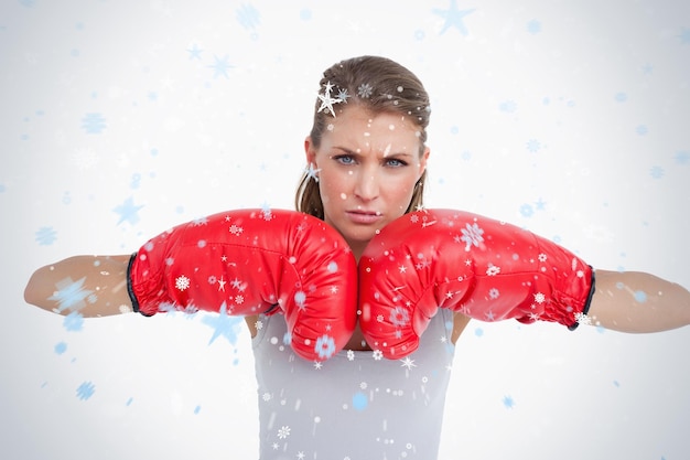 Mulher séria com luvas de boxe contra neve caindo