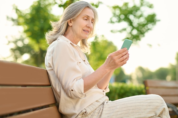 Mulher séria com smartphone no banco