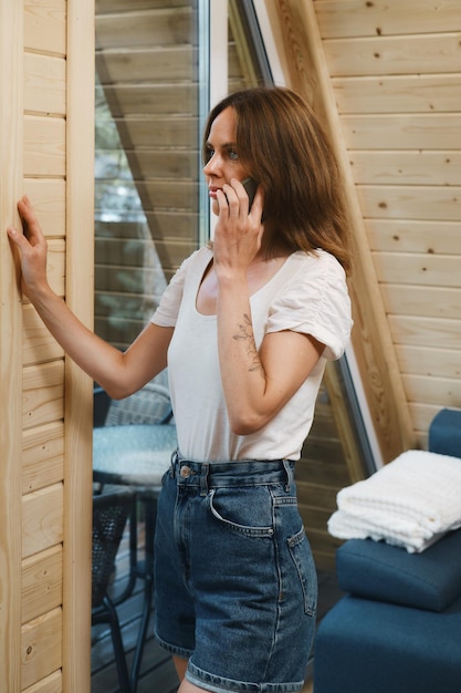 Foto mulher séria dentro de log aframe falando ao telefone pela janela