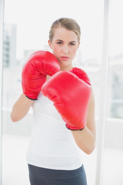 Mulher séria do ajuste com luvas vermelhas de boxe