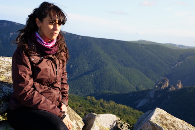 Mulher séria na colina de uma montanha contemplando a paisagem