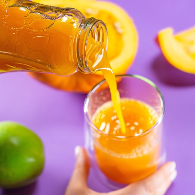 Mulher servindo suco de abóbora no copo