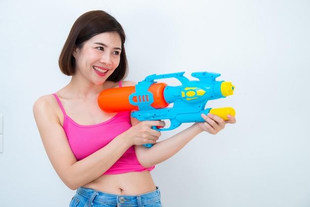 Mulher sexy asiática com água de arma na mão em fundo brancoFestival songkran day na tailândiaO melhor festival da tailândiaTerra do sorriso