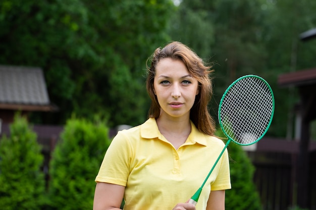 Mulher sexy atraente em pé com a raquete de badminton ao ar livre. morena esporte na natureza verde. Jogos ativos de esportes ao ar livre. Treino ao ar livre