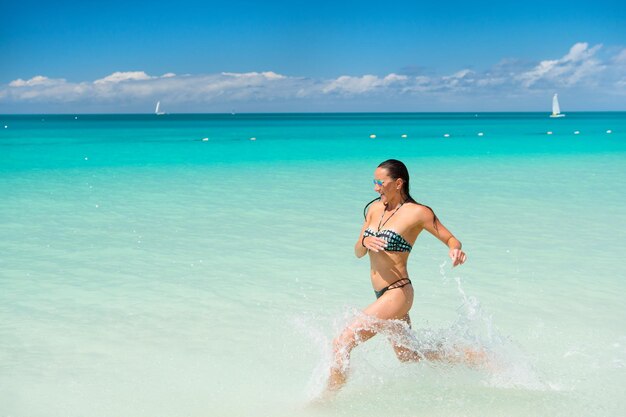 Mulher sexy correndo na água do mar em antigua