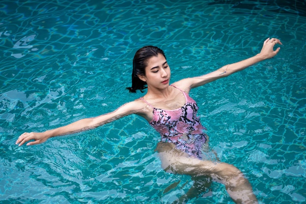 Mulher sexy da Ásia na piscina de biquíni Piscina bronzeada corpo magro e bem torneado Garota curtindo férias de viagem no bangalô sobre a água de luxo do resort