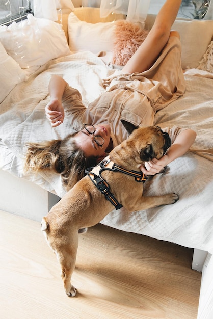 Mulher sexy e relaxada em uma cama de caravana pela manhã com o cachorro enquanto viaja e acampa
