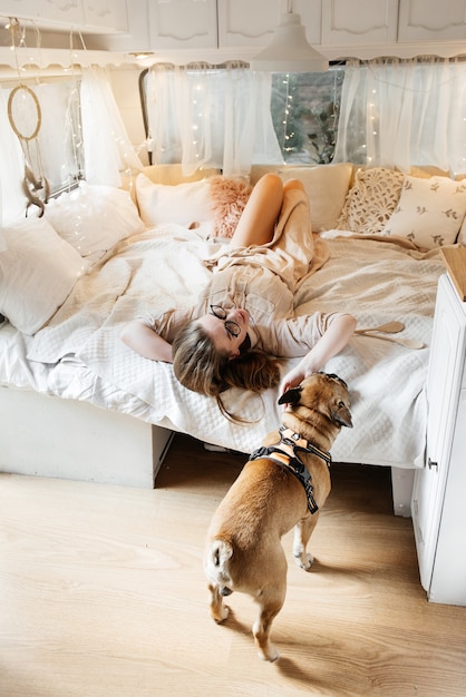 Foto mulher sexy e relaxada na cama do trailer pela manhã com um cachorro