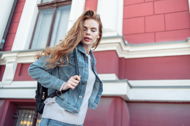 Mulher sexy elegante em roupas jeans e mochila na cidade