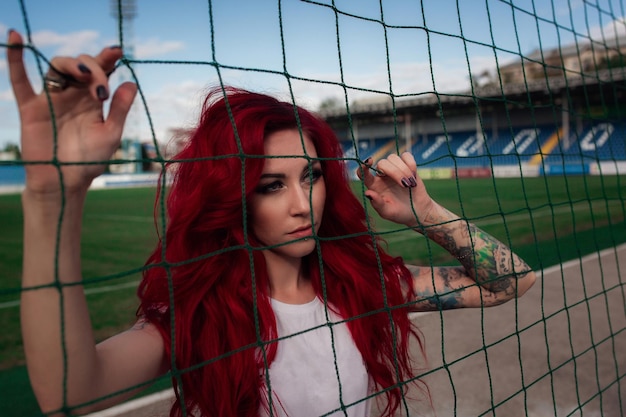 Mulher sexy fitness ou líder de torcida com uma bola de futebol Garota bonita e brilhante no campo de futebol uma combinação de beleza e força ron and roll