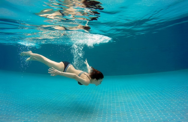 Mulher sexy nadando debaixo d'água em uma piscina em um dia de verão