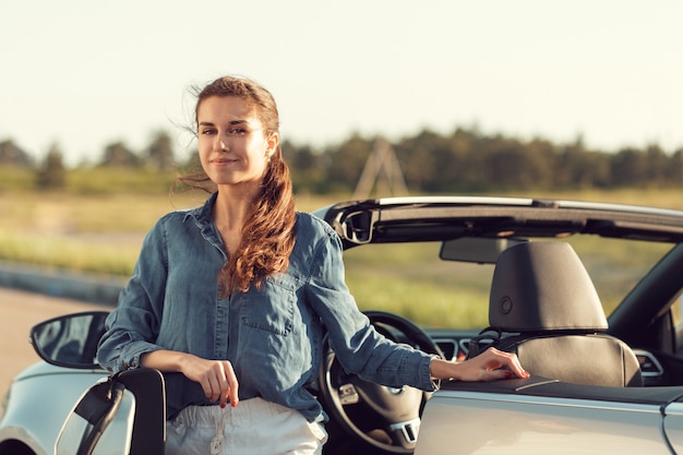 Mulher sexy, posando ao lado do carro cabrio