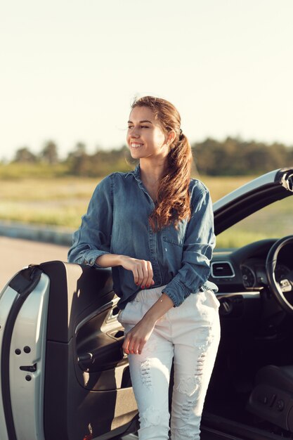 Mulher sexy, posando ao lado do carro cabrio