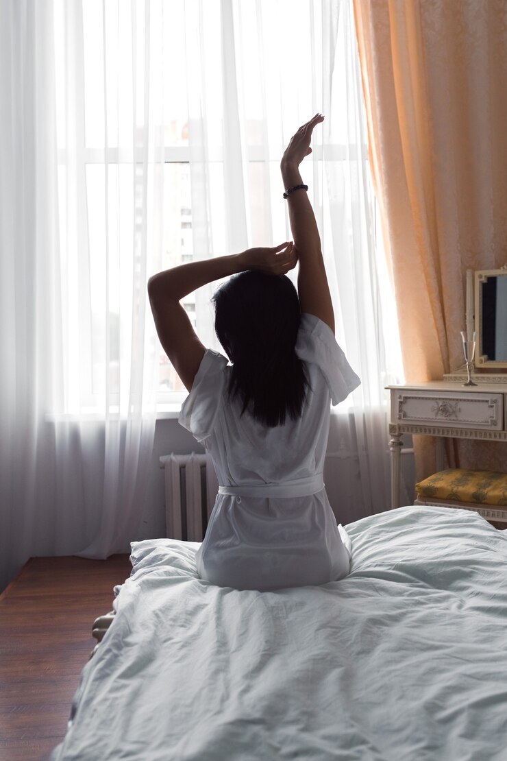 mulher sexy sentada na cama lençóis brancos vista traseira