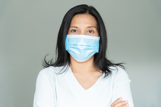 Mulher sob a máscara facial cobrindo a boca e o nariz. Conceito de Corona Virus ou COVID-19.
