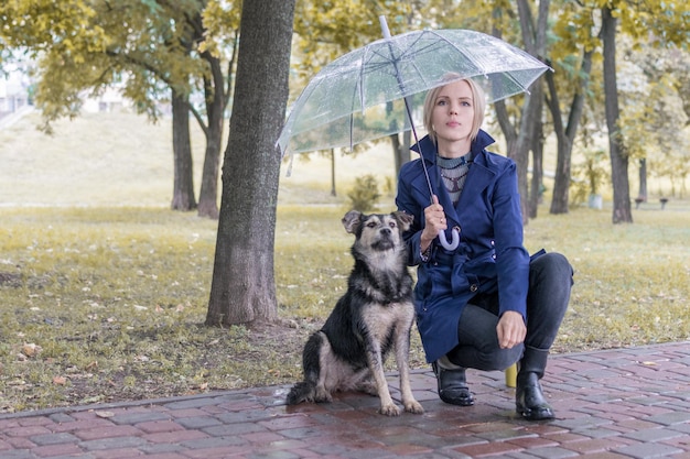 Mulher sob um guarda-chuva com um cachorro no parque Amizade de homem e cachorro