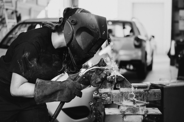 Mulher soldando uma peça de metal na garagem