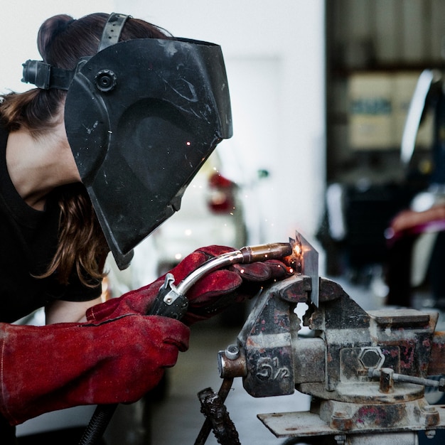 Mulher soldando uma peça de metal na garagem