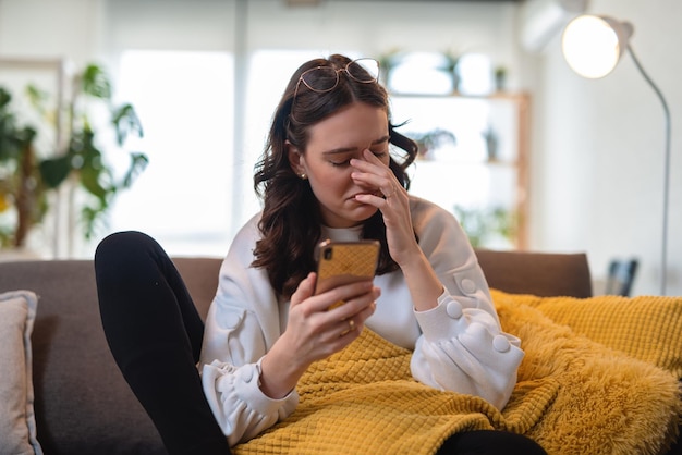 Mulher solitária com smartphone sentado no sofá em casa, esperando a mensagem do amante, copie o espaço