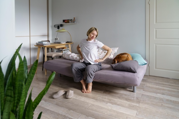 Mulher solteira feliz sentada no sofá com cachorro acordando cedo na manhã de fim de semana morando sozinha com animal de estimação