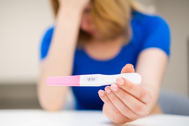 Mulher solteira triste segurando um teste de gravidez positivo