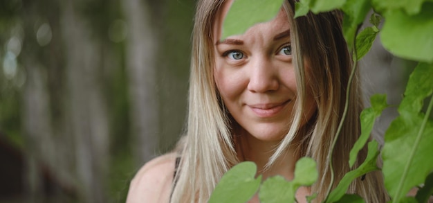 Mulher sonhadora olhando embora folhas verdes sobre fundo natural desfocado