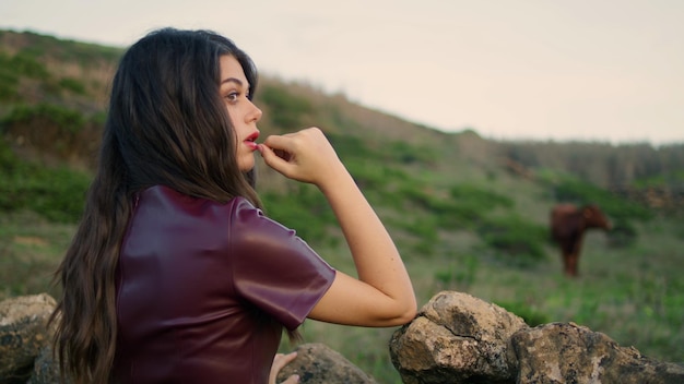 Mulher sonhadora posando encostada na cerca de pedra em clima sombrio sozinha de perto