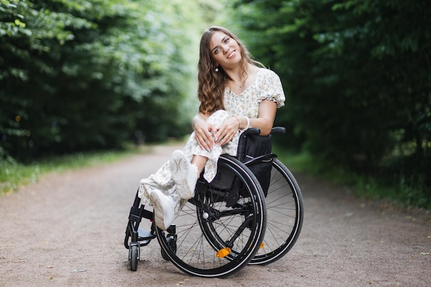 Mulher sonhadora sentada em cadeira de rodas entre o parque verde