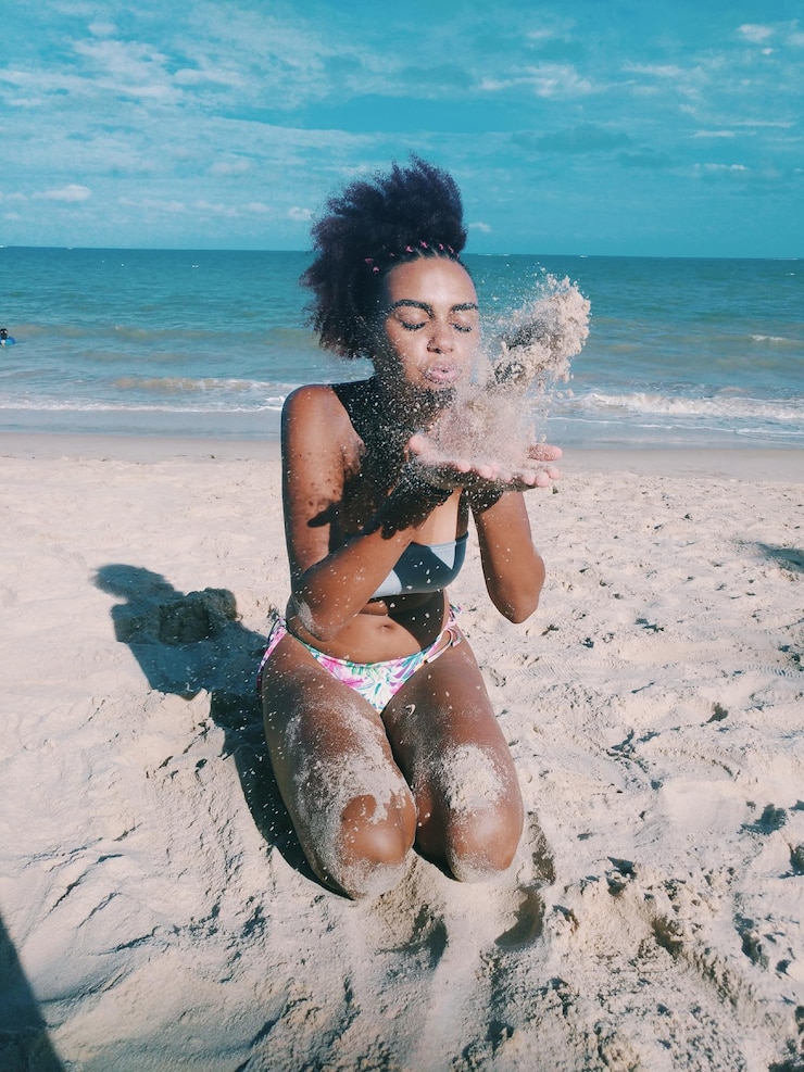 Foto mulher soprando areia na praia