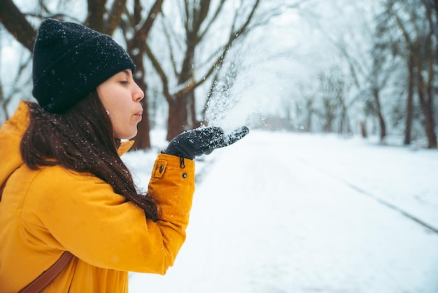 Mulher soprando neve de suas mãos nevou parque na temporada de inverno de fundo