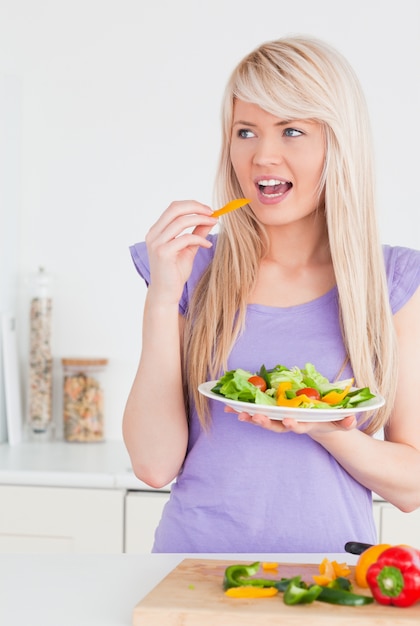 Mulher sorrateira atraente que aprecia sua salada